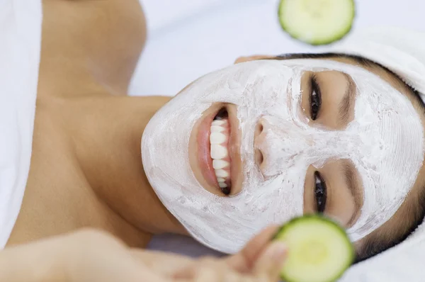 Woman with facial mask holding cucumber slices