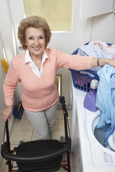 Senior Woman With Laundry By Washing Machine