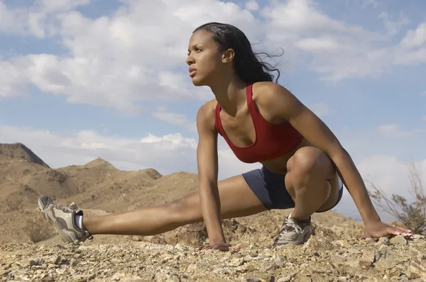 Female Jogger Stretching In Mountains