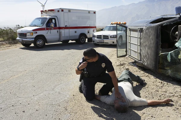 Policeman Checking Pulse Of Car Crash Victim