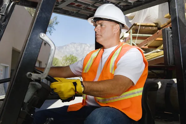 Confident Worker Driving Forklift At Workplace
