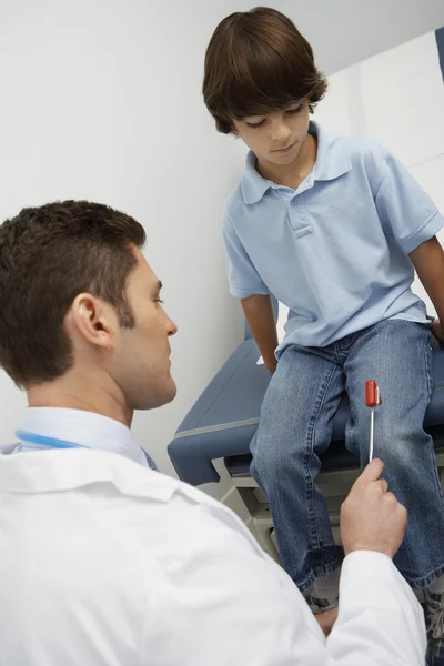Doctor Examining Boy With Reflex Hammer