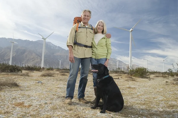 Senior Couple With Dog Near Wind Farm