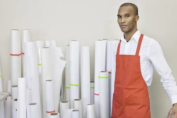 Portrait of printing press worker standing with paper rolls in background