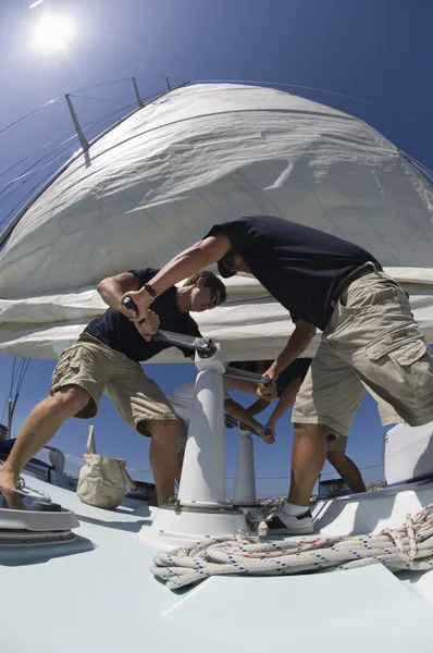 Sailors operating windlass on yacht