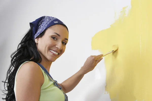 Woman painting the wall yellow