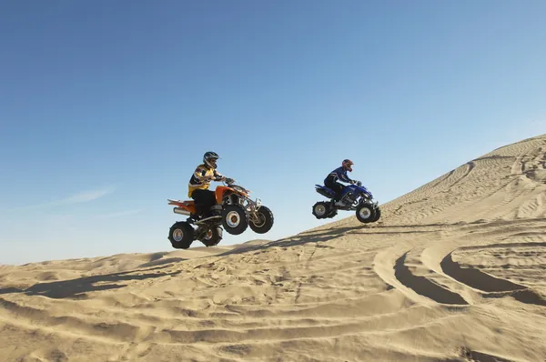 Men doing wheelies on quad bikes