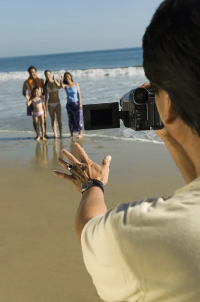 Man filming family on beach