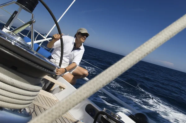 Sailor at helm of yacht on ocean
