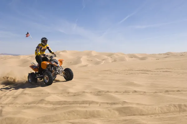 Man Riding ATV Over Sand Dune