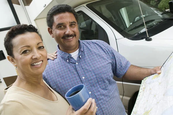 Mid-adult couple standing beside caravan