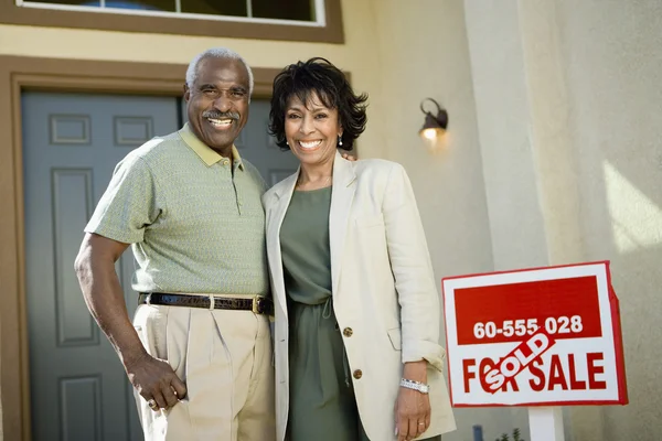 Couple standing by sold real estate sign