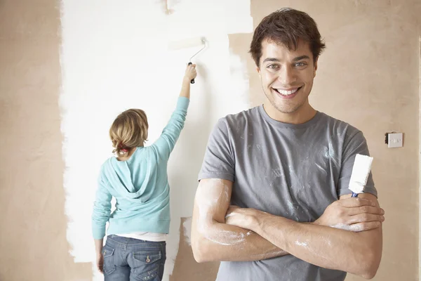 Couple painting interior wall