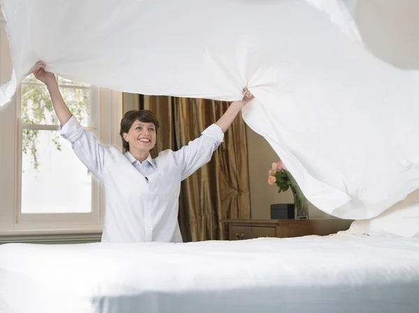 Smiling woman making bed
