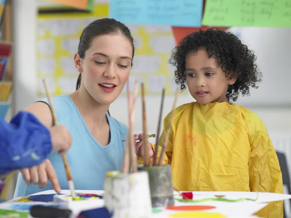Art teacher with little girl painting
