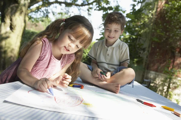 Young boy and girl drawing in garden