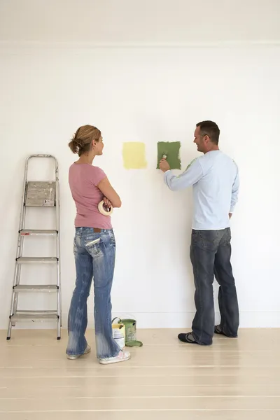 Woman watching man testing paint colours