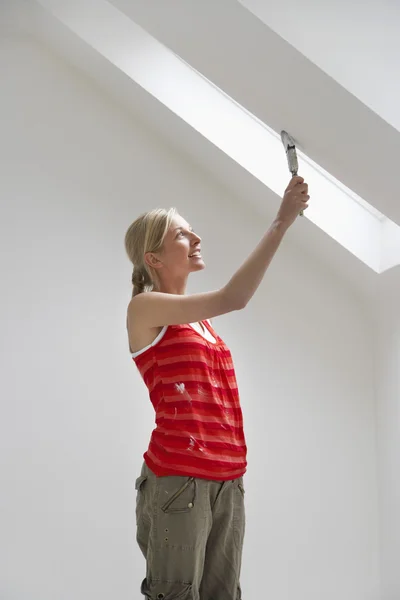 Woman painting sloping ceiling