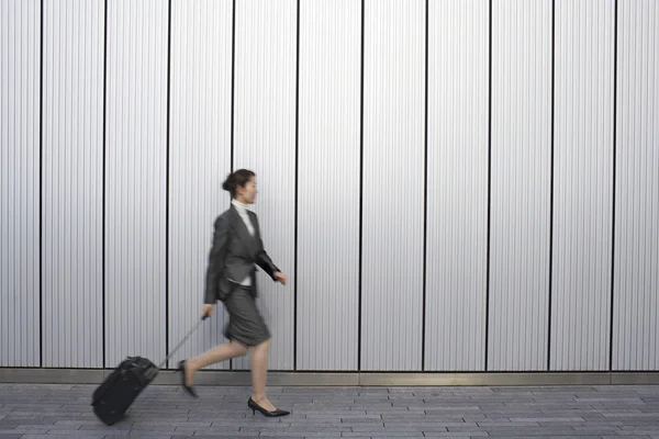 Businesswoman walking pulling suitcase