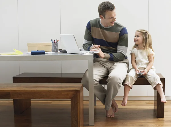 Father and daughter with laptop and cell phone