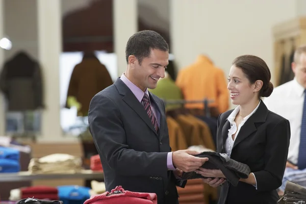 Salesperson assisting businessman in clothes store