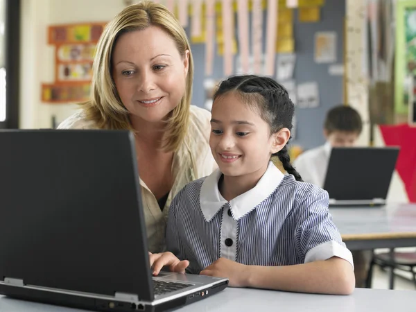 Teacher helping student with laptop