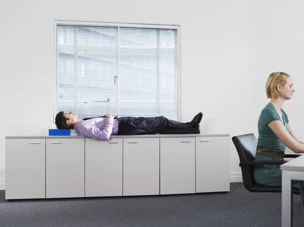 Businessman sleeping on office cabinets