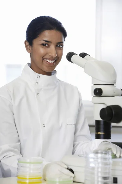 Female lab worker standing by microscope