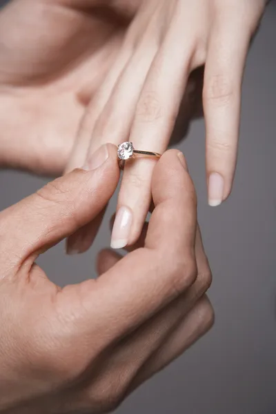 Man placing engagement ring on woman\'s finger