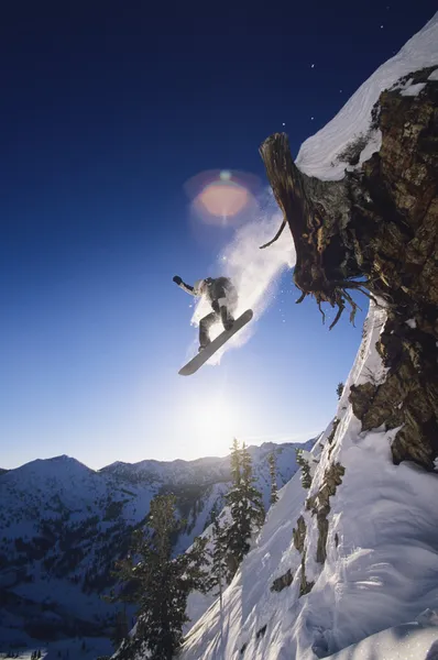 Snowboarder jumping from mountain ledge