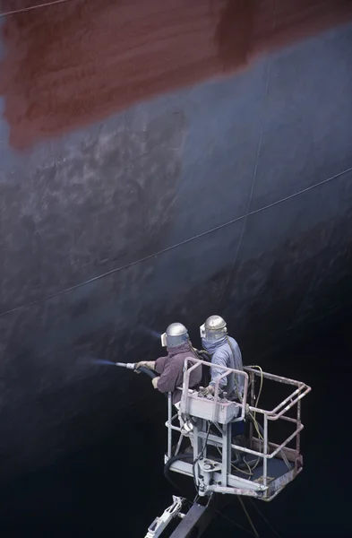 People Painting a Large Ship