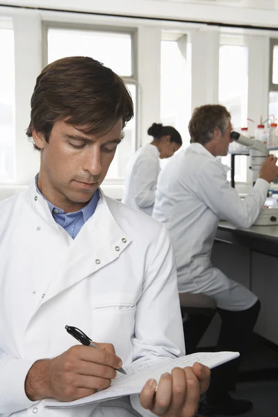 Lab Worker Writing on Notepad