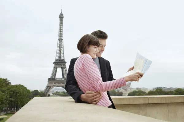 Couple reading map in front of Eiffel Tower