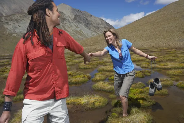 Man helping woman wade through pond