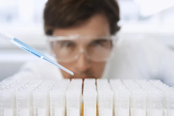 Male lab worker adding drops to test tubes