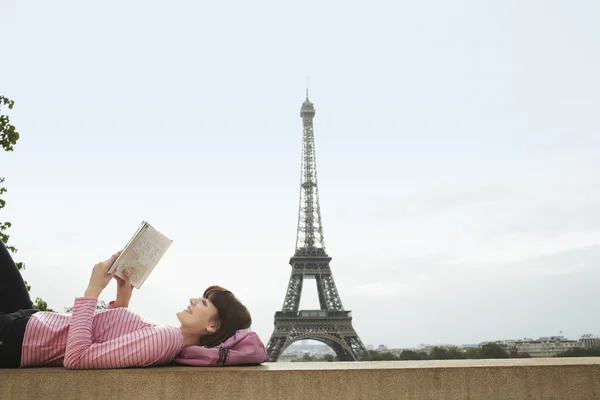 Woman reading book in front of Eiffel Tower
