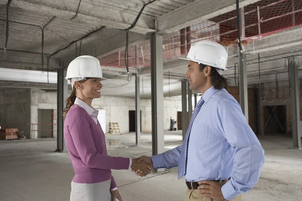 Woman and man shaking hands at construction site