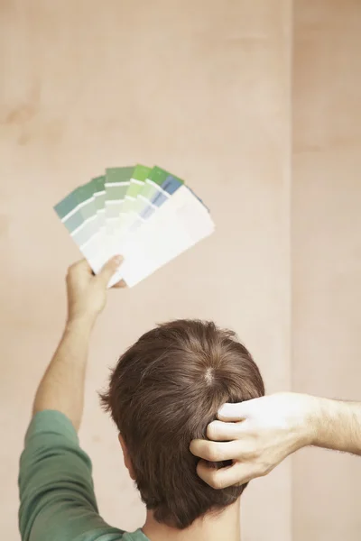 Man looking at paint colour swatches