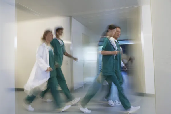 Physicians rushing through hospital Corridor