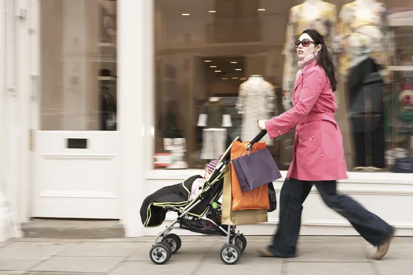Mother pushing stroller by shop