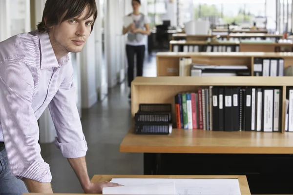 Architect studying blueprint in office