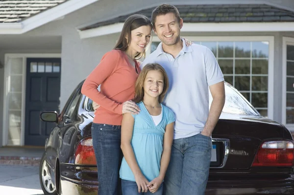 Family outside house with car