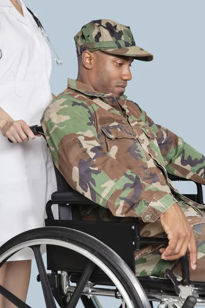 Soldier in wheelchair assisted by female nurse