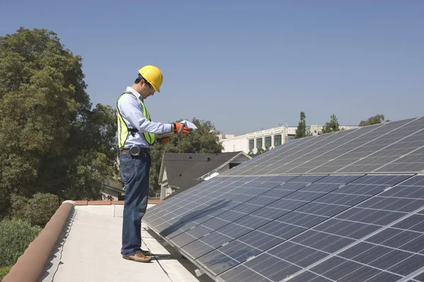 Maintenance worker stands with solar array on rooftop