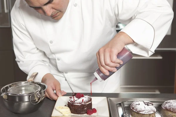 Mid- adult chef puts finishing touches on chocolate cake