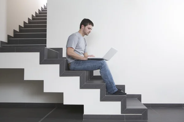 Man sits on staircase with laptop