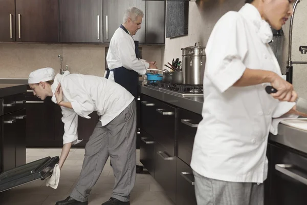 Three chefs work together in busy kitchen