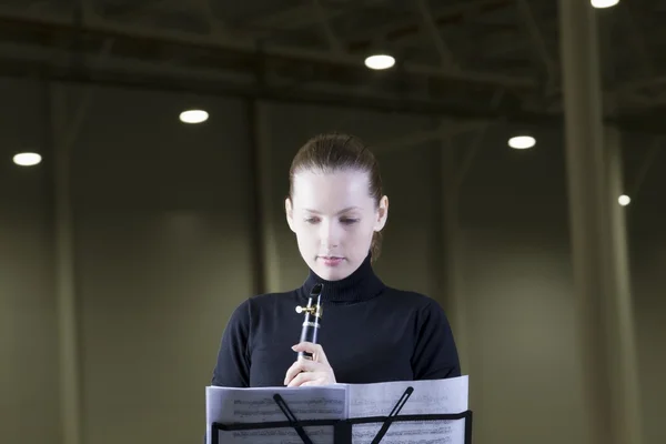 Clarinet player stands with sheet music under spotlights