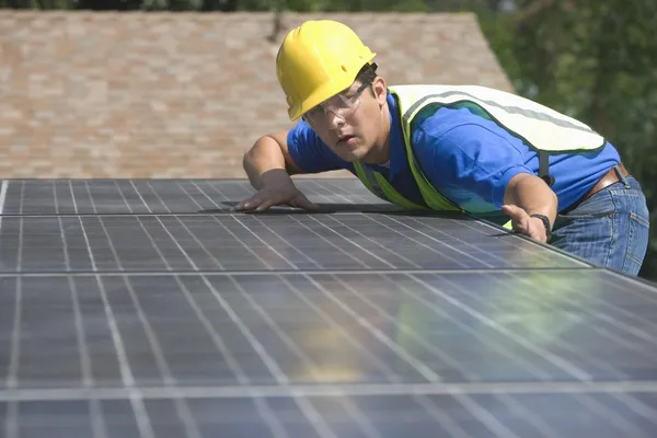 Maintenance worker measures solar array on rooftop