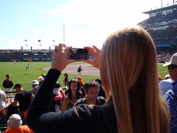 Lady uses Iphone to Photograph baseball game from the crowd